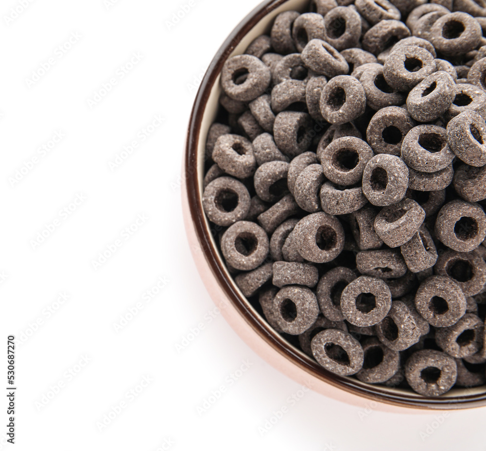 Bowl with tasty black cereal rings on white background, top view