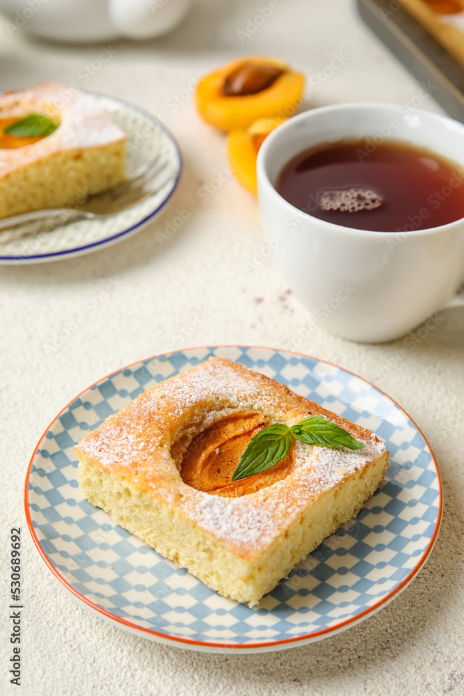 Plate with piece of tasty apricot pie and tea on light background