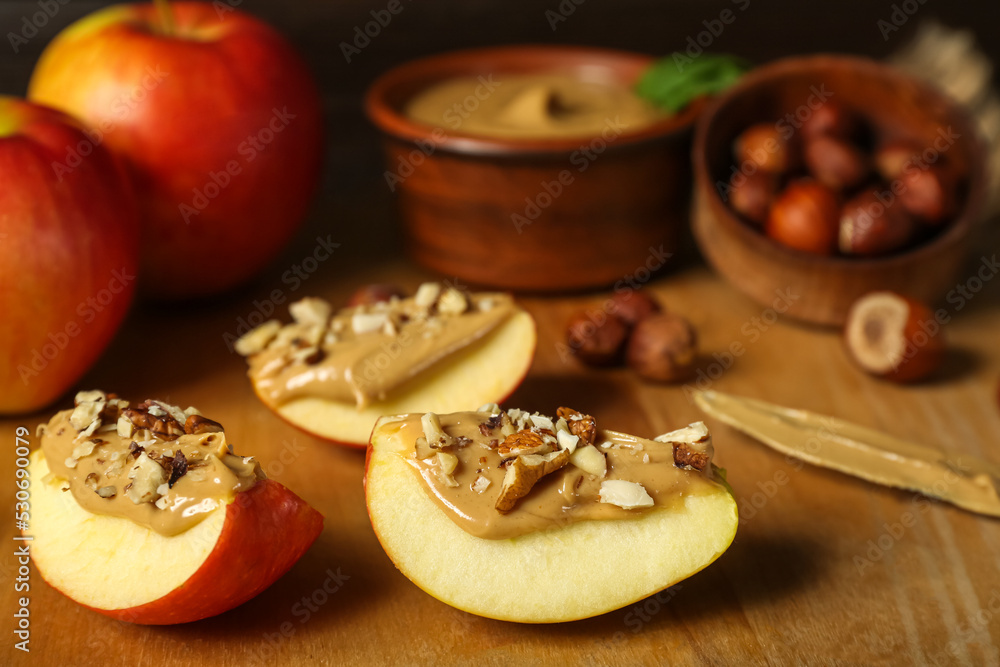 Wooden board of tasty apple wedges with nut butter, closeup