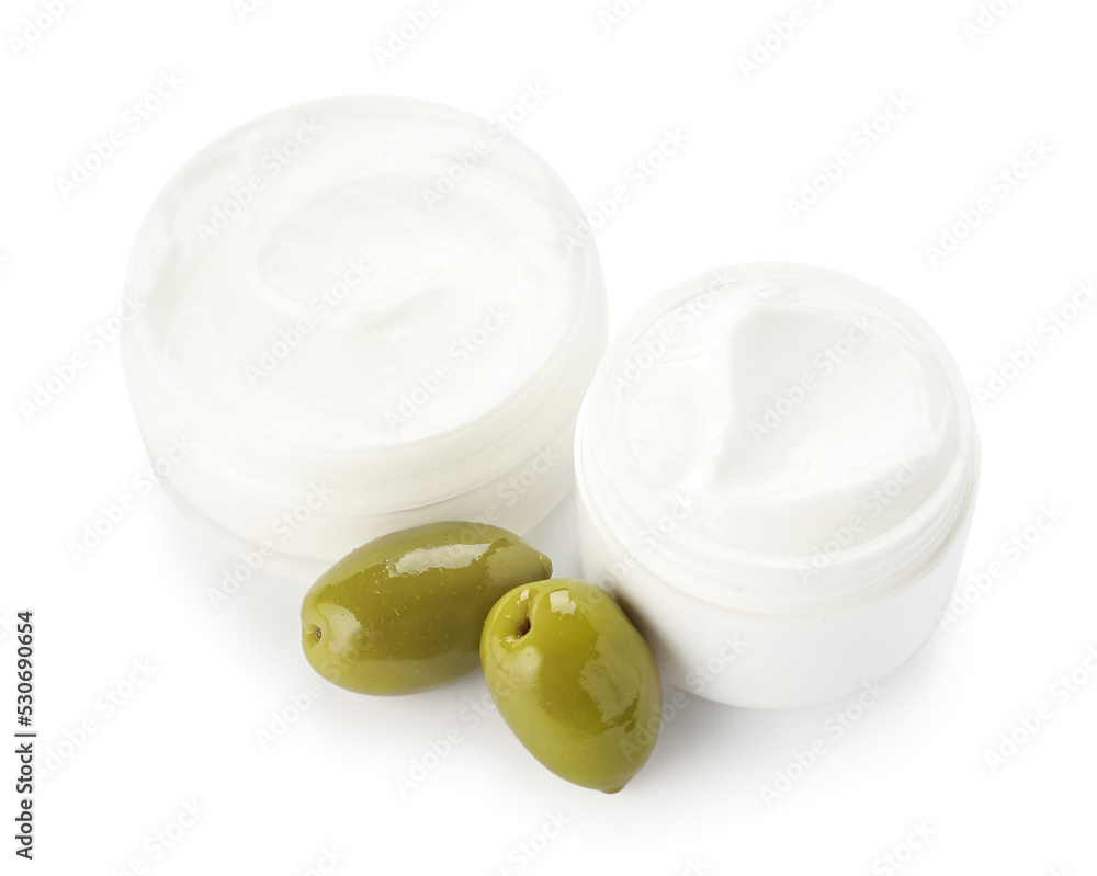 Jars of cream with green olives on white background