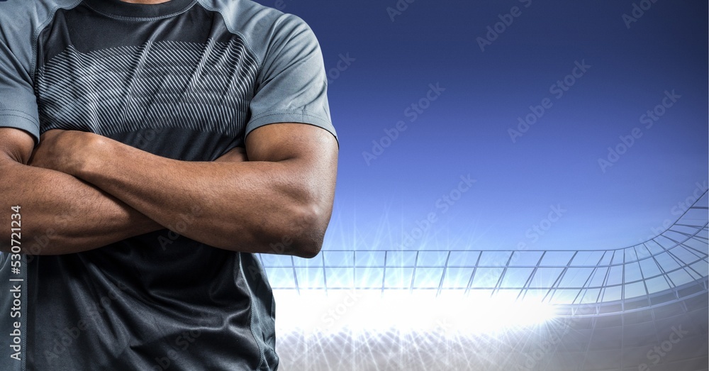 Composition of male rugby player with arms crossed over sports stadium