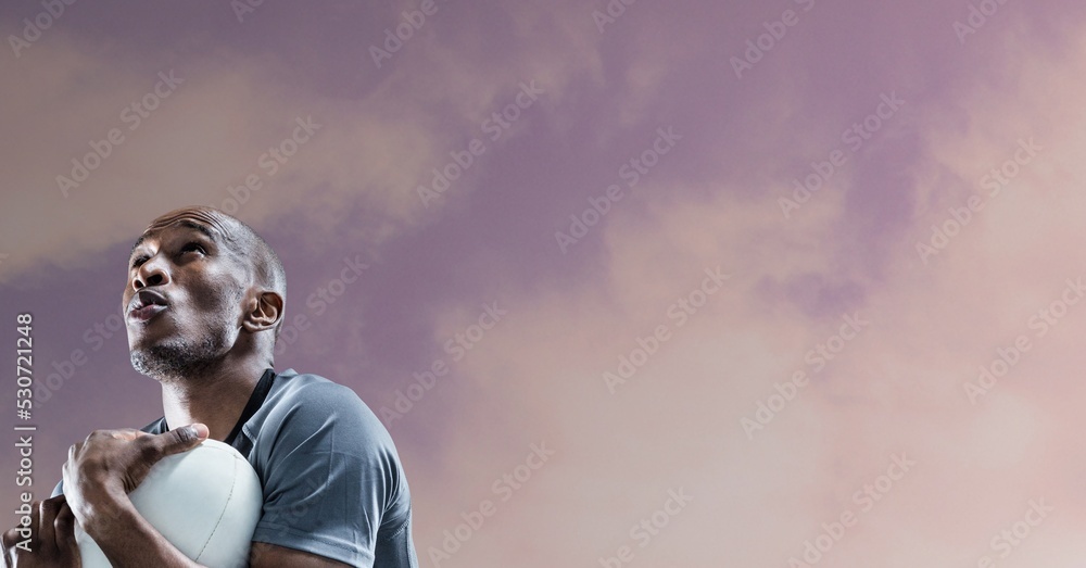 Composition of male rugby player holding rugby ball over blue sky with clouds