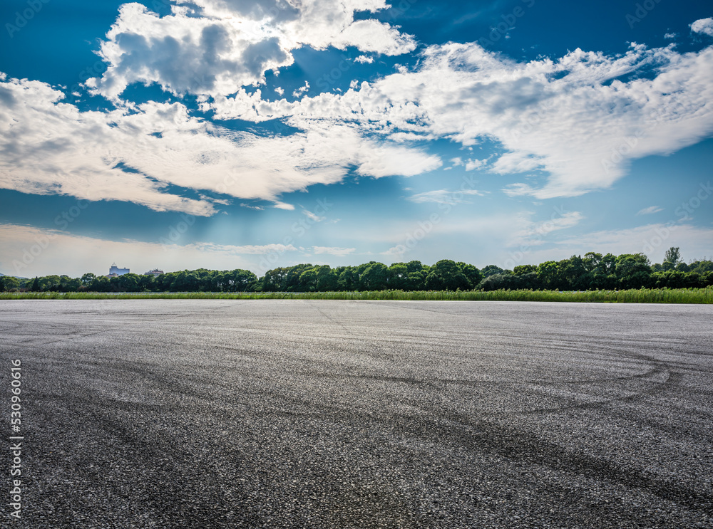 空旷的沥青赛道道路和天空云朵背景的绿色森林