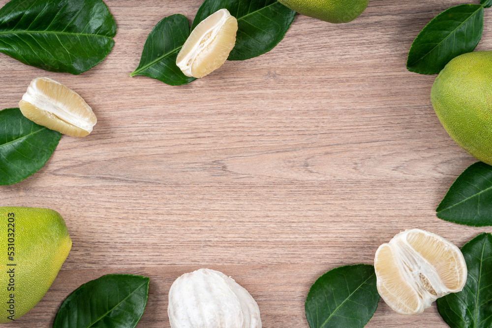 Fresh pomelo fruit on bright wooden table background.