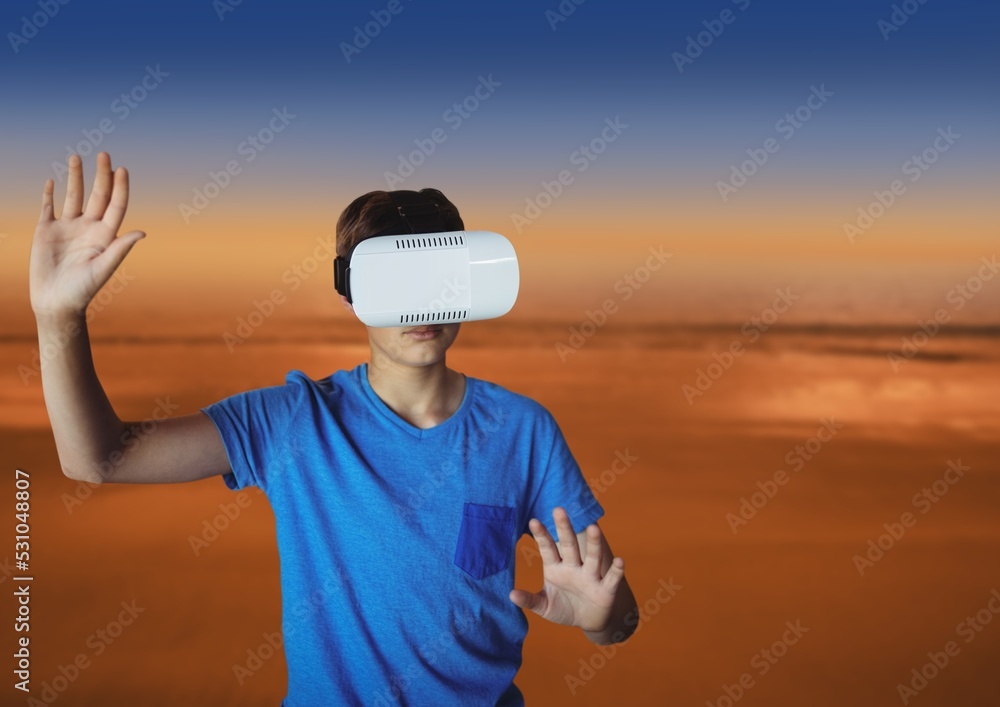 Composite image of caucasian boy wearing a vr headset against sunset sky