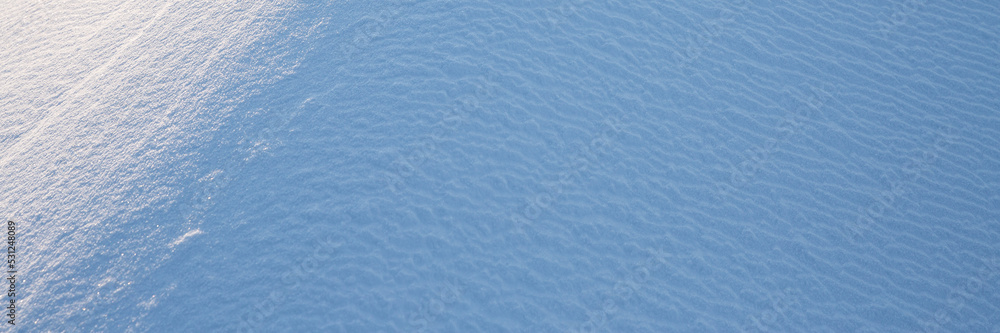 Beautiful winter background with snowy ground. Natural snow texture. Wind sculpted patterns on snow 