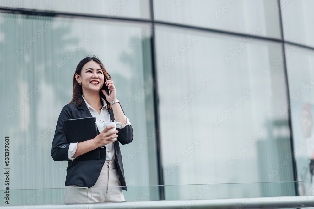 Young Asian businesswoman talking on phone and sitting in airport before business trip. Beautiful wo