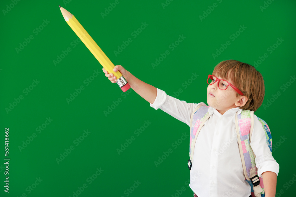 Happy child student against green chalkboard