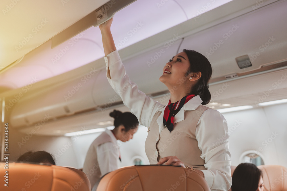 The stewardess helps the passengers to put their luggage in the cabin of the plane. Stewardess in th