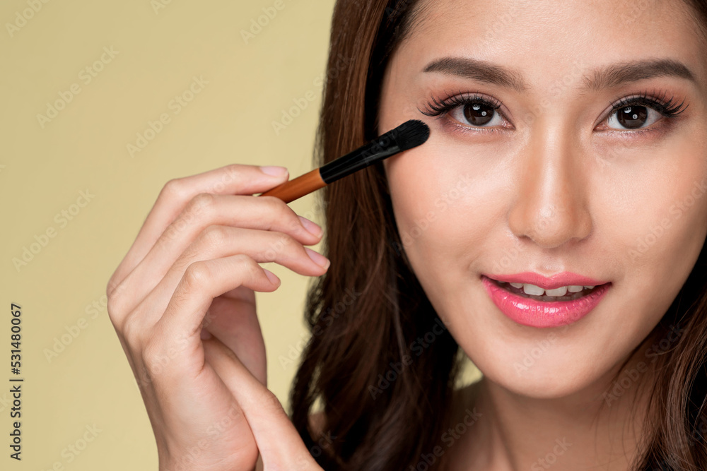 Closeup ardent young woman with healthy fair skin applying her eyeshadow with brush. Female model wi