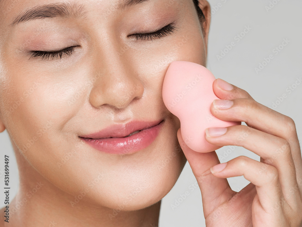 Closeup ardent woman applying her cheek with dry powder and looking at camera. Portrait of younger w