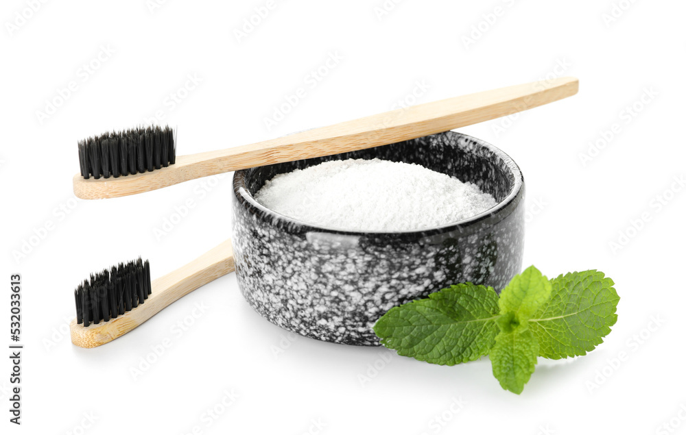 Bowl of tooth powder with mint and brushes on white background