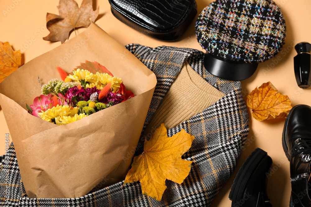 Female clothes, accessories, bouquet of flowers and autumn leaves on beige background