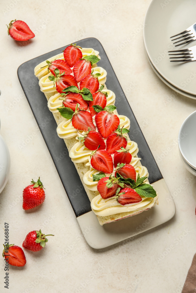 Plate of tasty roll cake with fresh strawberry on light background