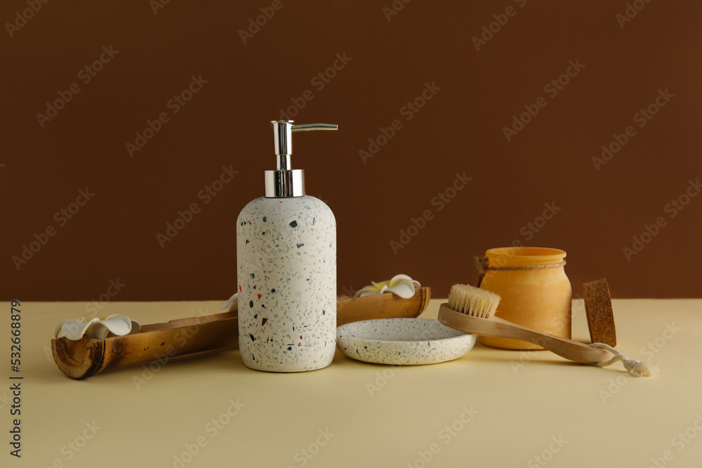 Bath accessories with flowers on table near brown wall