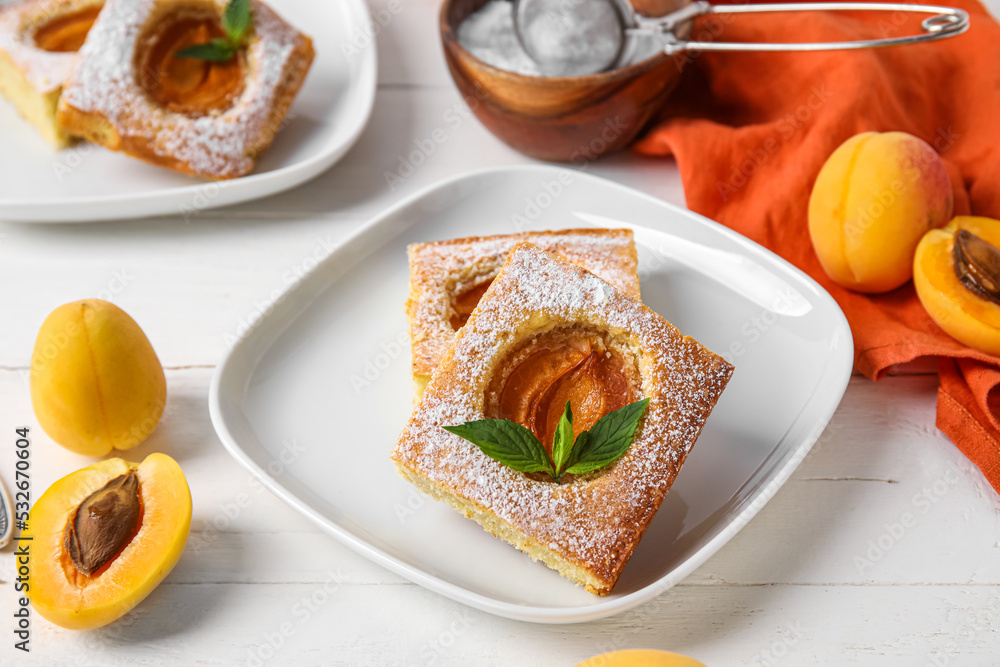 Plate with pieces of tasty apricot pie on light wooden background, closeup