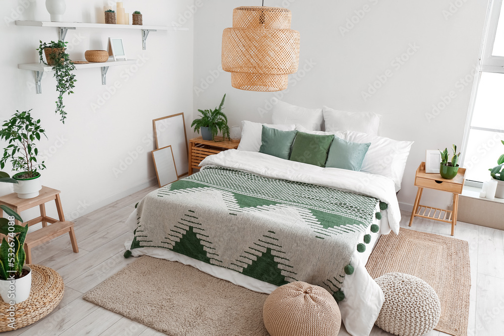 Interior of light bedroom with houseplants and poufs