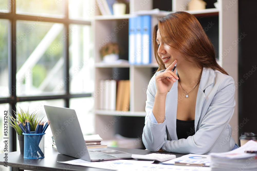 Attractive young businesswoman working with laptop at her desk in office.