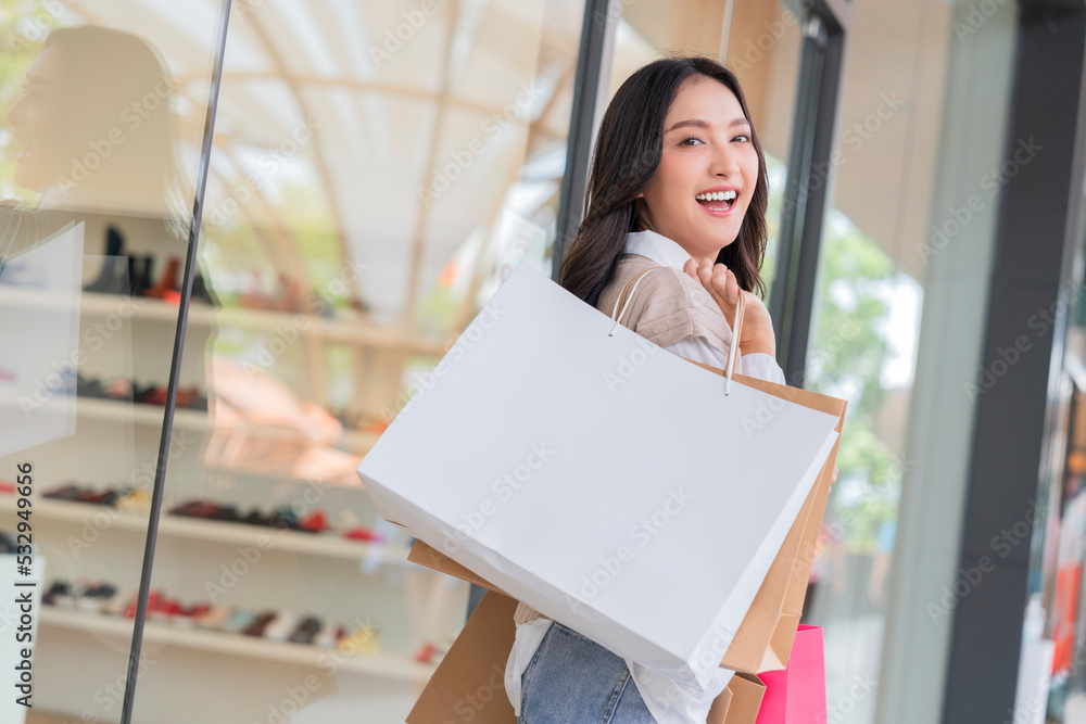 快乐微笑的亚洲女女孩拿着一堆购物袋，女性购物后回家