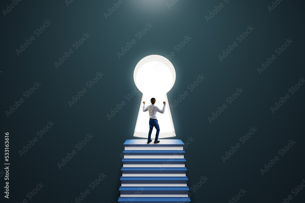 Back view of thoughtful young male standing on stacked books ladder in concrete interior and looking