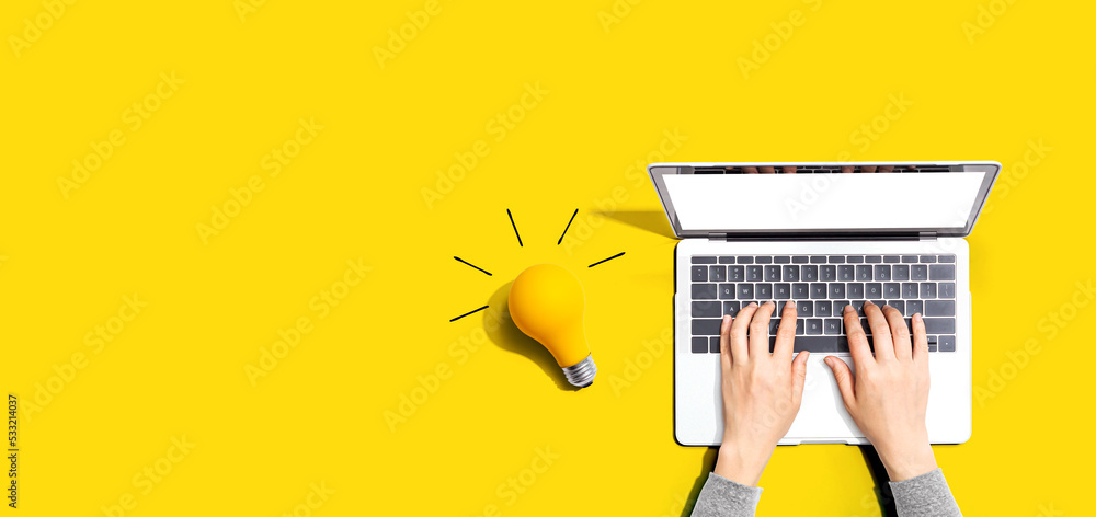 Person using a laptop computer and a light bulb - Flat lay