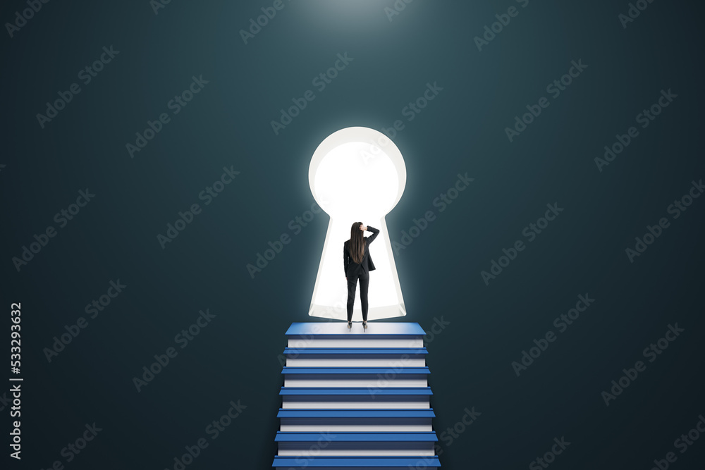 Back view of thoughtful young female standing on stacked books ladder in concrete interior and looki