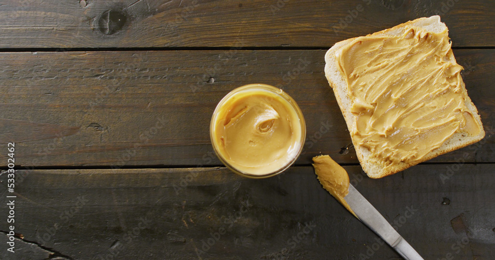 Image of close up of toast with peanut butter on wooden background