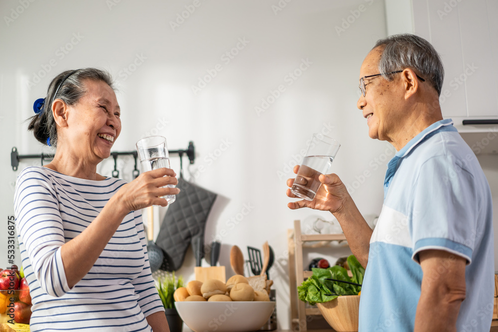 亚洲一对老年夫妇在家里的厨房里喝了一杯水。