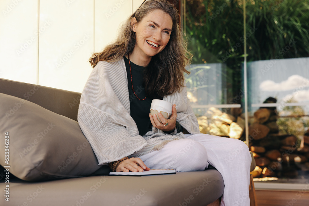 Cheerful senior woman journaling with a cup of tea at home