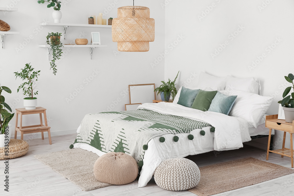 Interior of light bedroom with houseplants and poufs