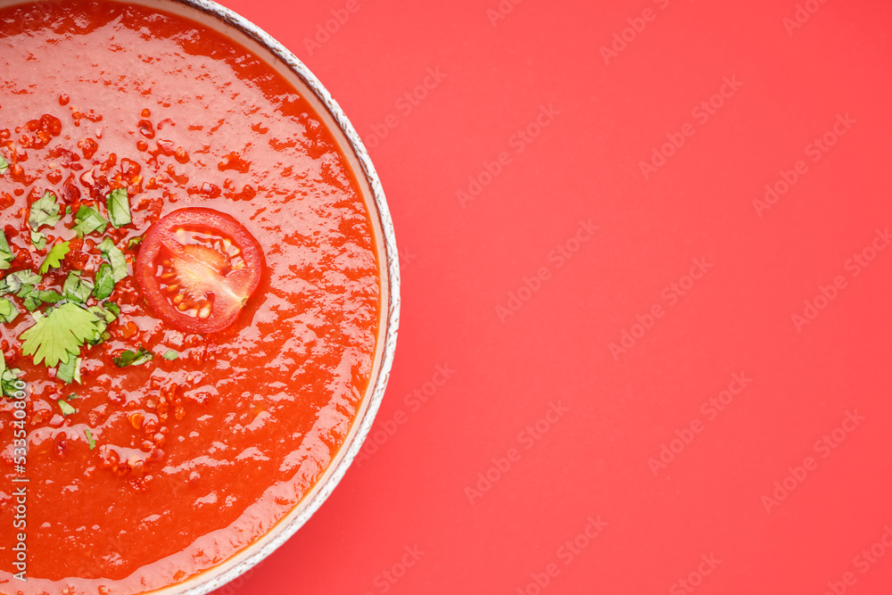 Bowl of tasty tomato soup on red background, closeup