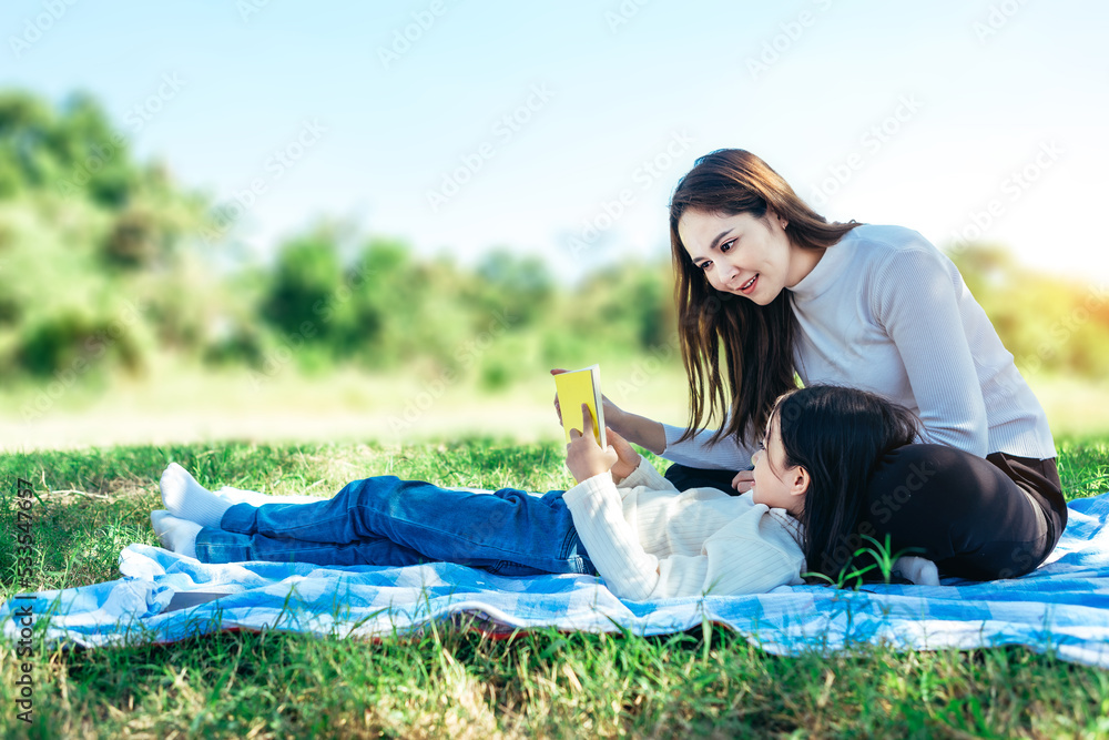 Happy asian family mom and her doughter in the garden, They are having fun and reading book together