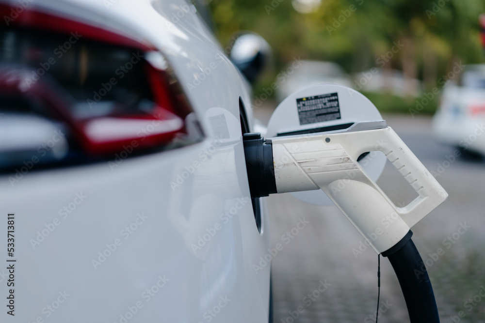 Electric car is charging in parking lot