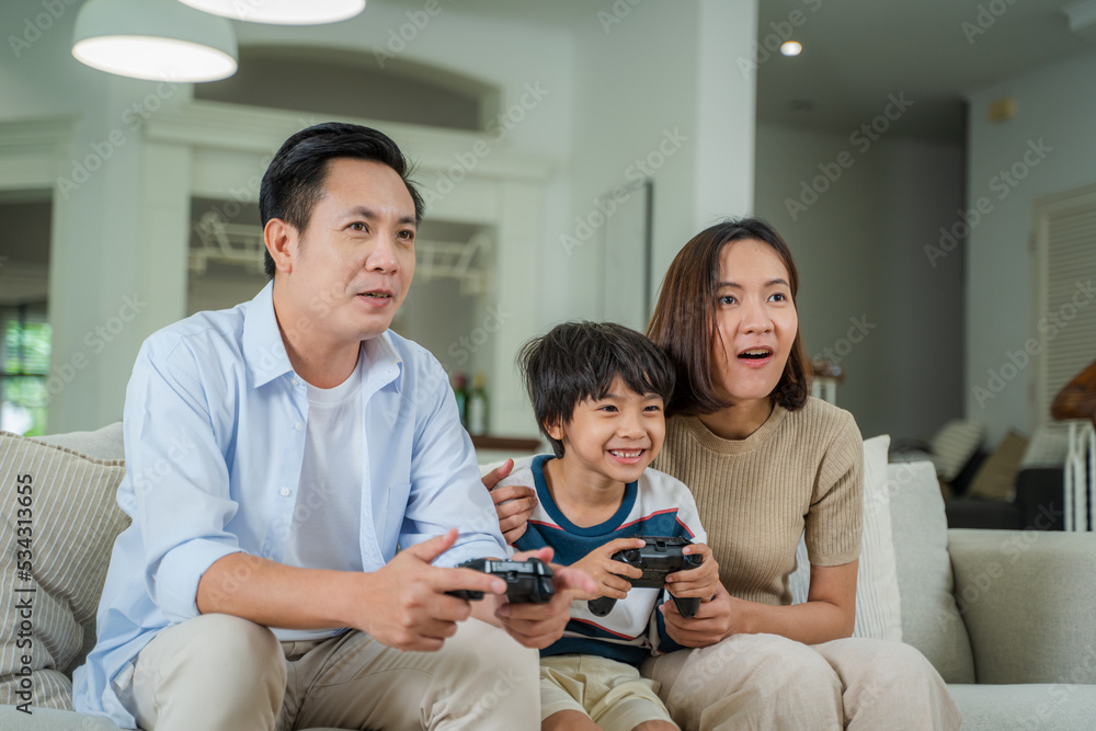 Family sitting on the couch together playing video games,Joyful family enjoying spending weekend fre