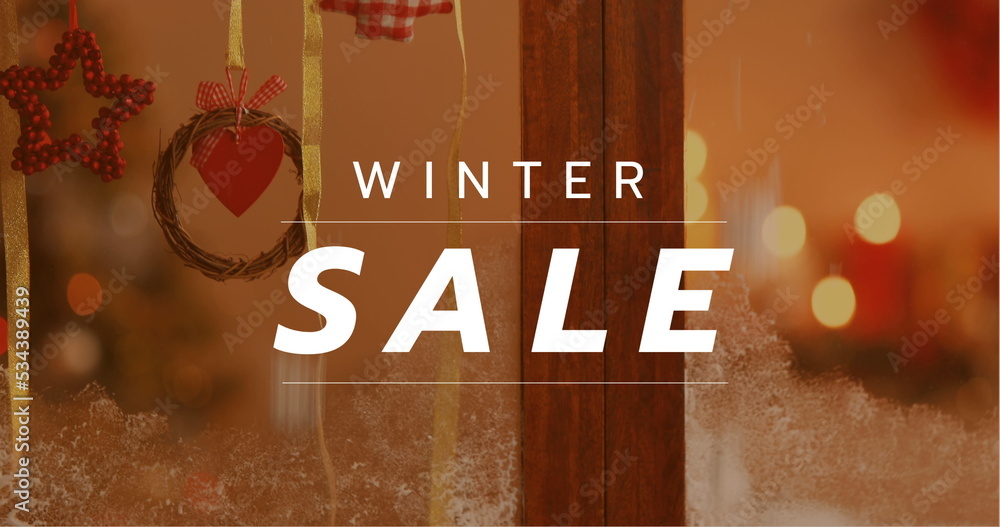 Composition of winter sale text over christmas window decoration in background