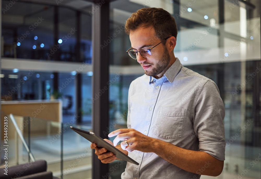 Man in office, working on tablet at night in the office and testing campaign strategy for marketing 