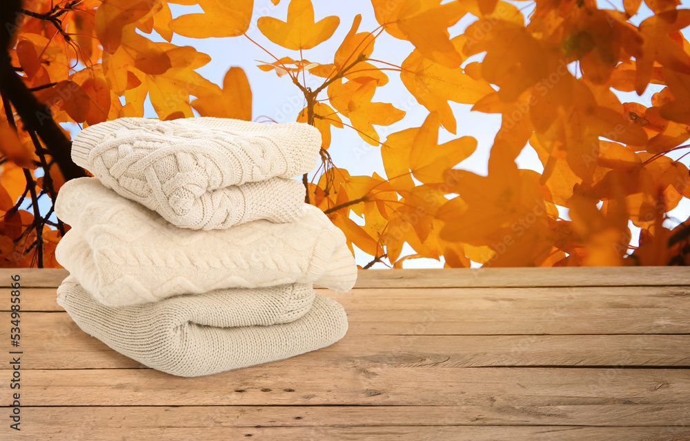 Stack of warm sweaters on table in autumn garden