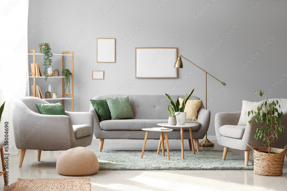 Interior of modern living room with houseplants, sofa and armchairs