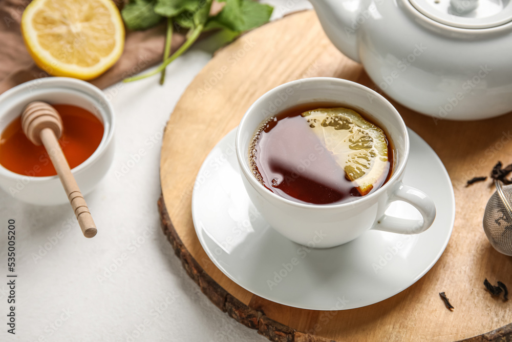 Board with cup of black tea and lemon on white background, closeup