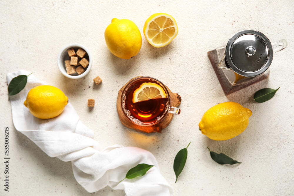 Glass cup of black tea with lemon, cane sugar and teapot on white background