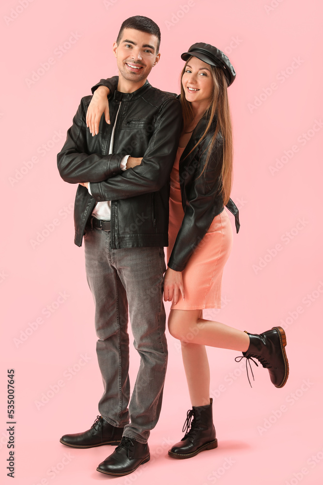 Fashionable young couple in autumn clothes on pink background