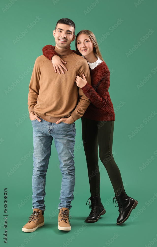 Fashionable young couple in autumn clothes on green background