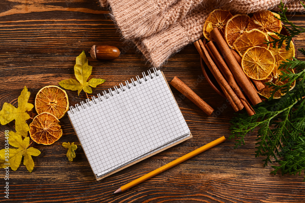 Notebook, pencil and autumn decor wooden background