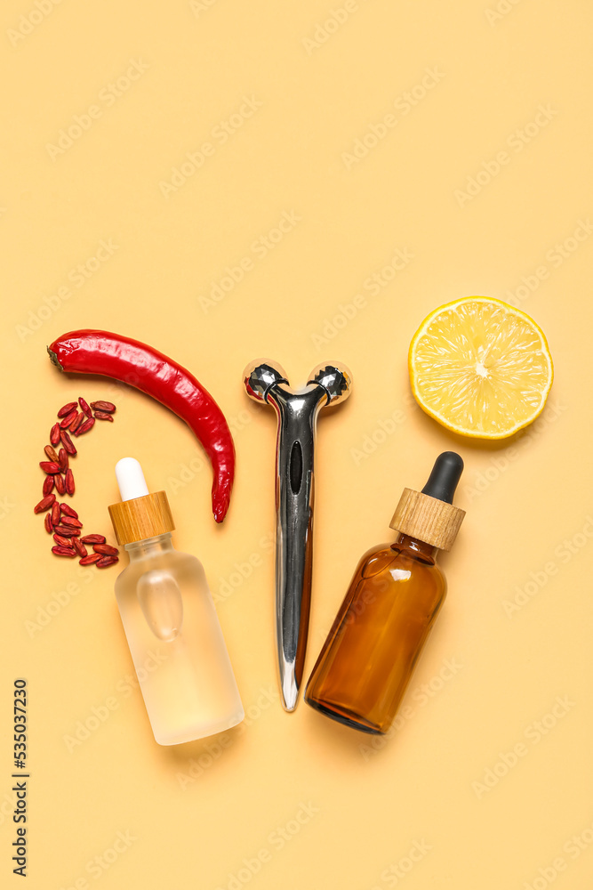 Facial massage tool with cosmetic dropper bottles and natural components on beige background