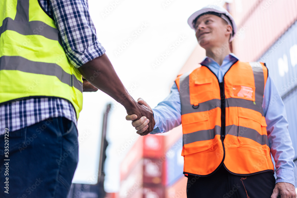 Caucasian businessman and African man worker working in container port. 