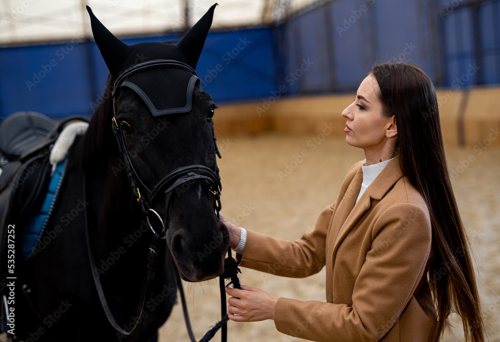 Pretty young lady with horse. Portrait of female jockey woth horse.