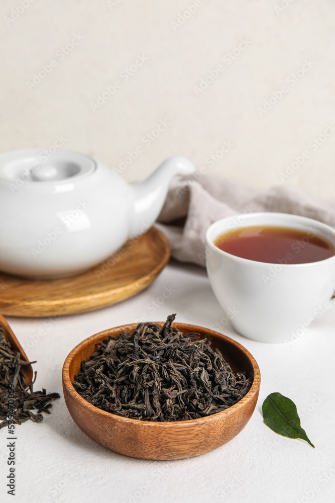 Composition with dry tea leaves and hot beverage on white table