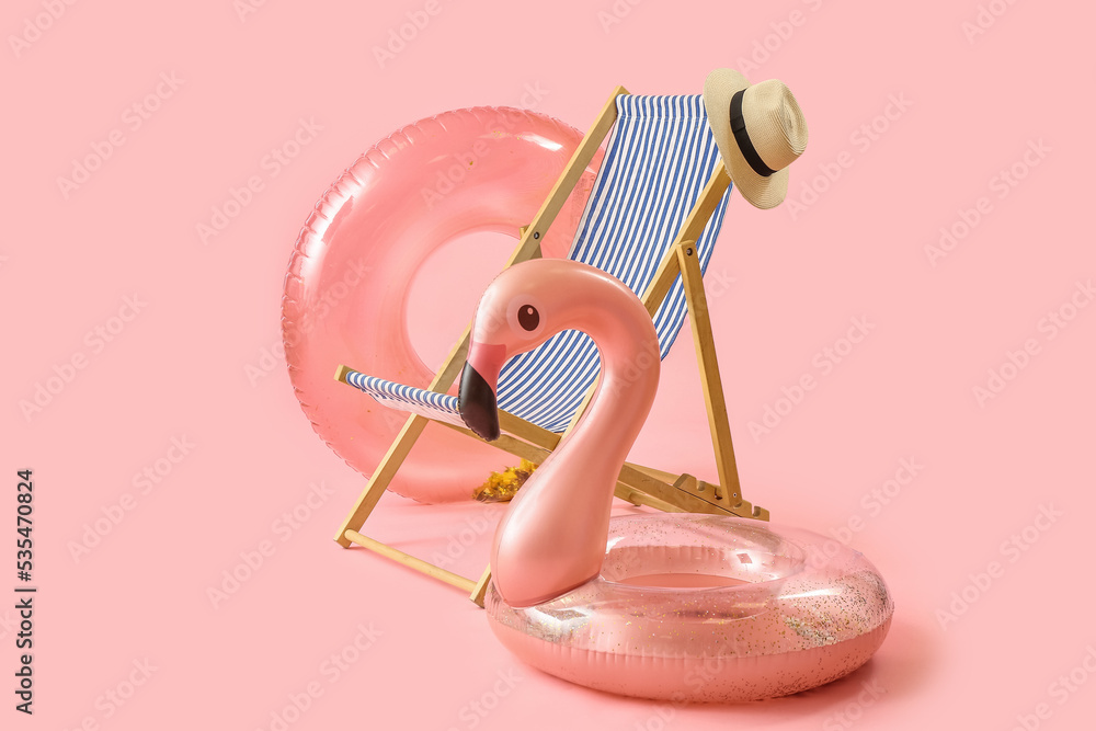 Deck chair and beach accessories on pink background