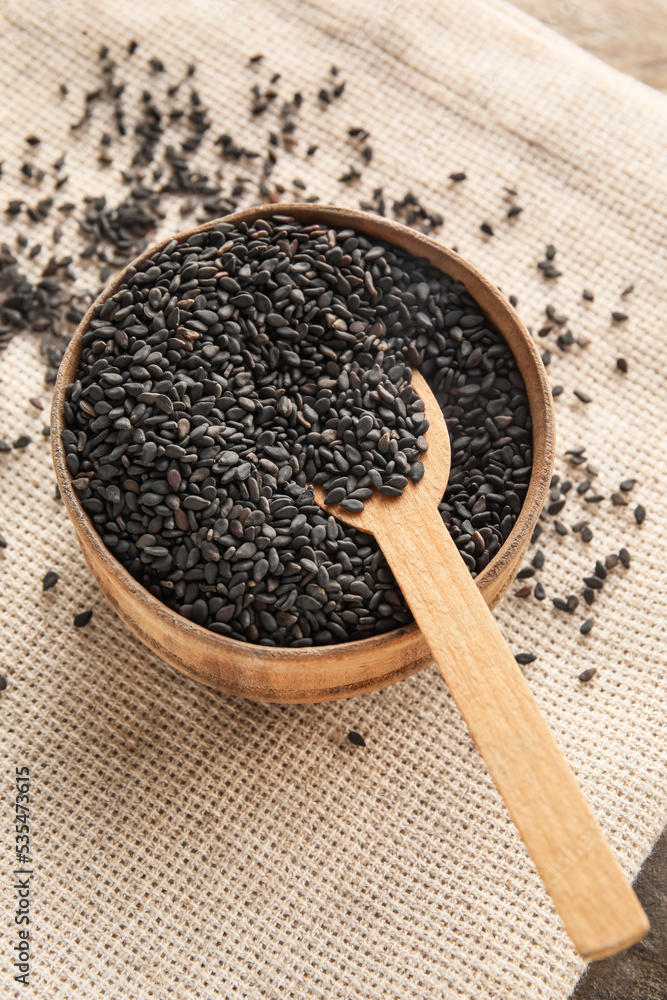 Wooden bowl of black sesame seeds on table, closeup