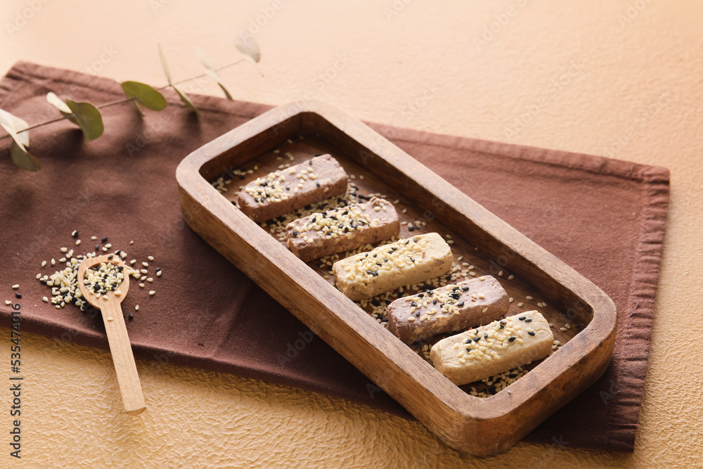 Wooden board with tasty sesame halva on color background